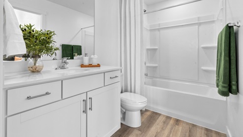 Bathroom with white cabinets and countertops and shower surround.