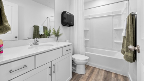 Primary bathroom with white cabinets and countertops and shower surround.