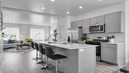 View from the dining area through the kitchen to the living room with large windows bringing in a lot of brightness and light.