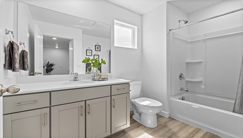 Large full size bathroom with a window and plenty of counterspace at the sink location, toilet and tub shower combination.