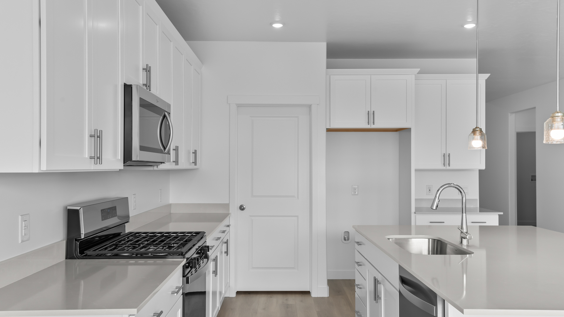 Kitchen with island, white cabinets and countertops, and stainless steel appliances.