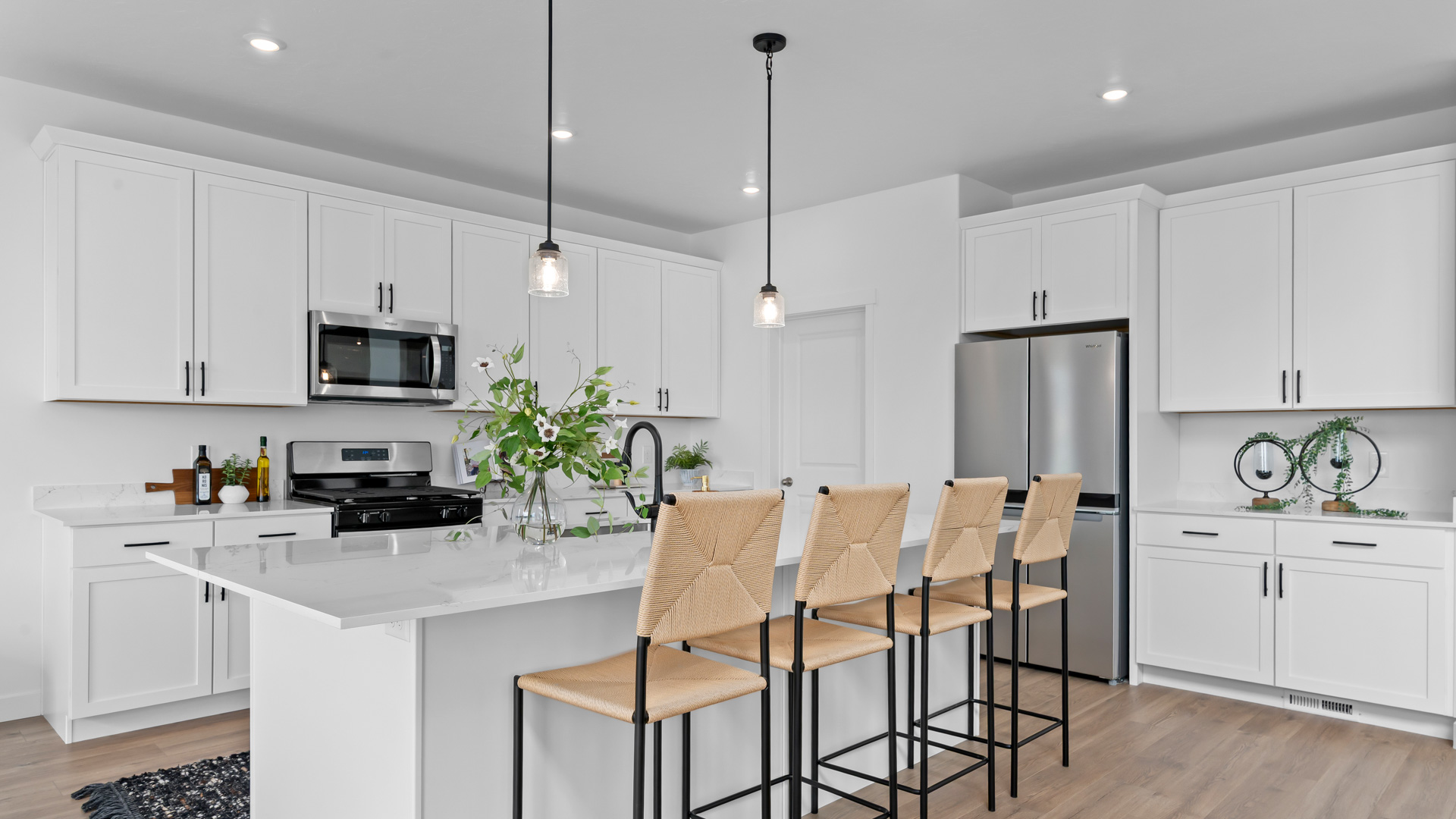 Spacious kitchen with quartz countertops, pendant lighting and stainless steel appliances.