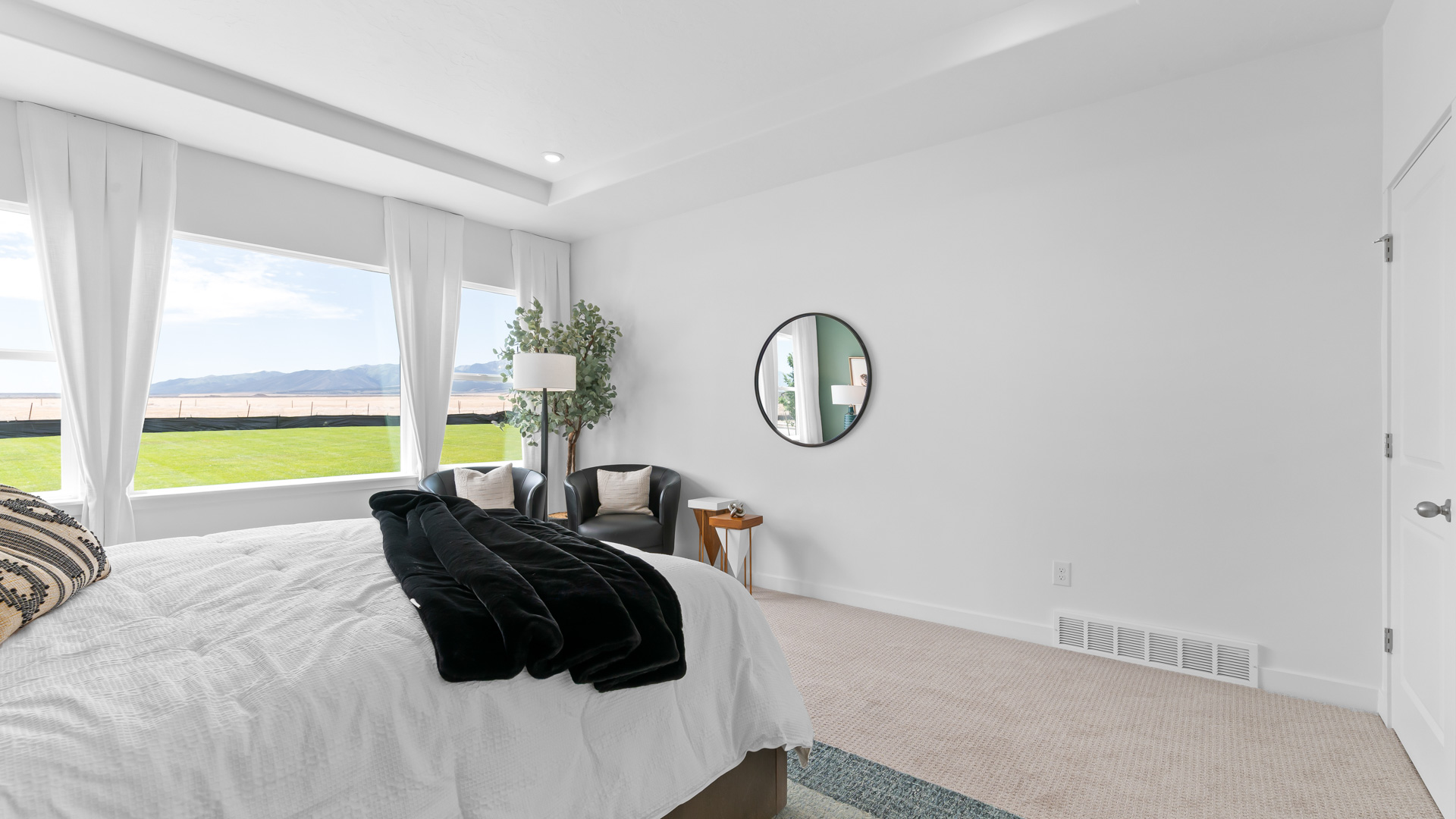 Primary bedroom with tray ceiling, recessed lighting, and large picture window.