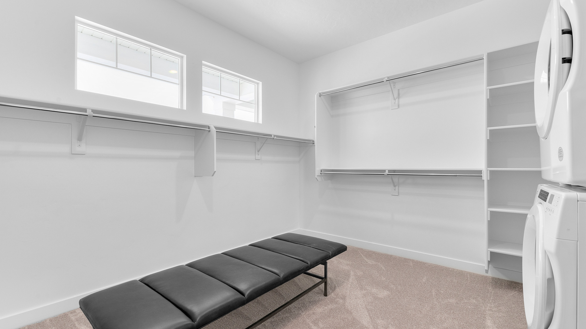 Large walk-in closet with windows and laundry unit.