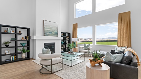 Main living space with two story windows and fireplace.