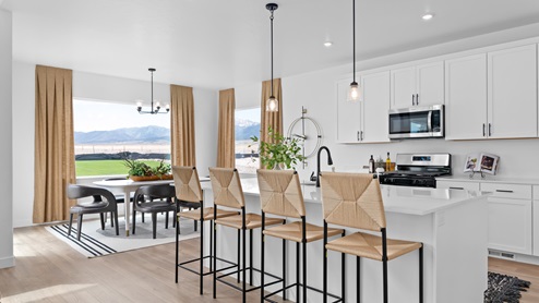 Spacious kitchen with white cabinets and countertops, kitchen island, and stainless steel appliances.