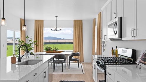 Spacious kitchen with white cabinets and countertops, kitchen island, and stainless steel appliances.