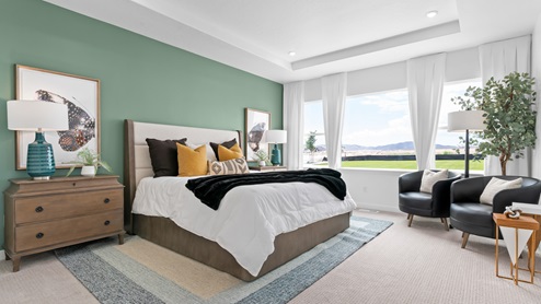 Primary bedroom with tray ceiling and large windows.