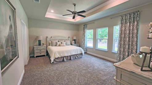 The Castine model home primary bedroom with windows and trey ceiling.