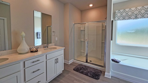 The Castine model home primary bathroom with dual vanity, garden tub and standing shower.