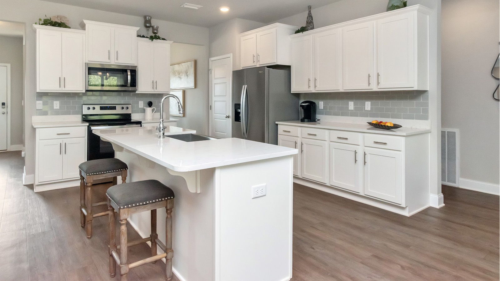 A stylish kitchen with granite countertops and white cabinetry highlights the Katherine floorplan on the Mississippi Gulf Coast.