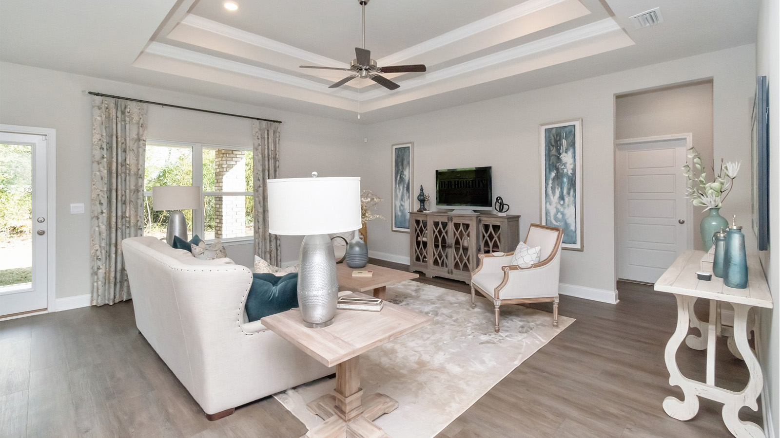 Spacious open living space with ceiling fan and neutral furnishings in a D.R. Horton home.