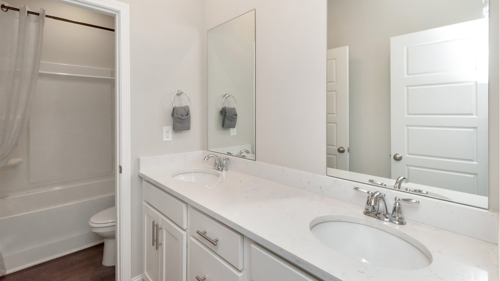 Dual sinks and white cabinetry bring function and style to this shared Jack and Jill bathroom on the Mississippi Gulf Coast.