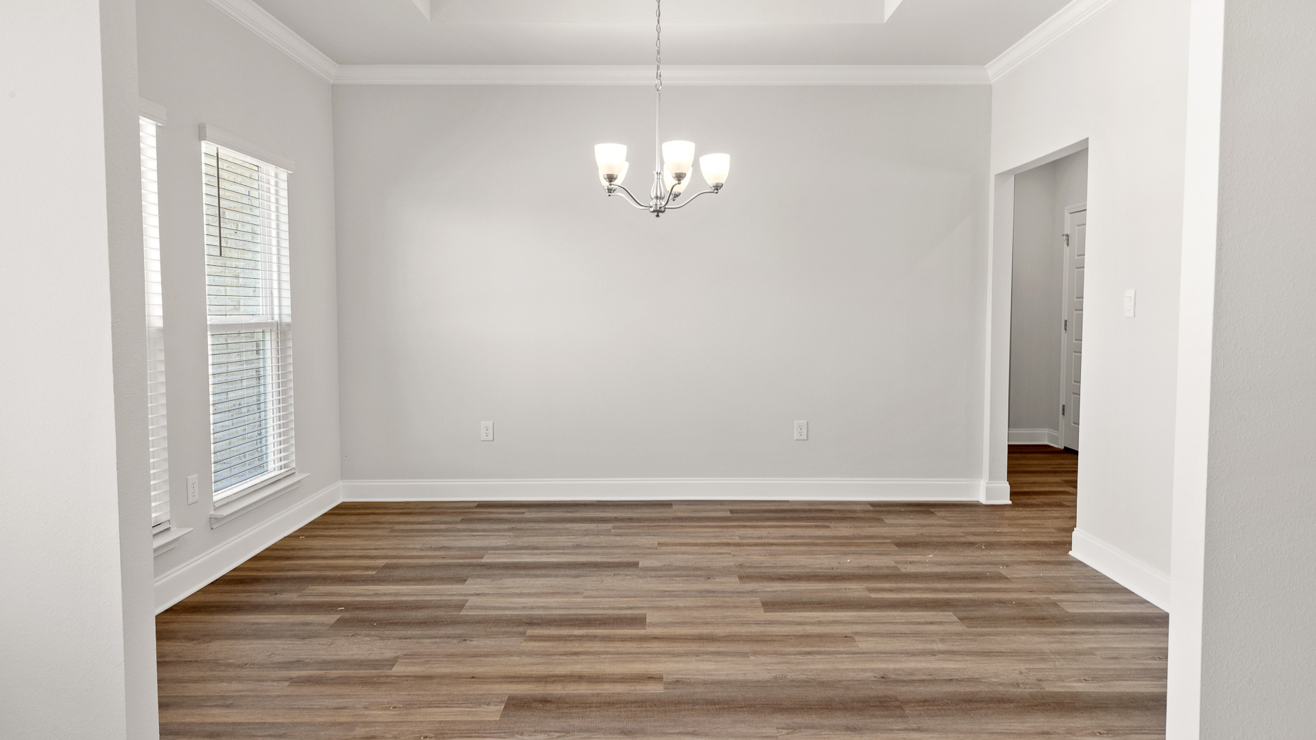 Formal dining room with LVP floors and chandelier.