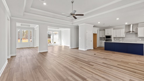 Open living space with large tray ceiling and luxury vinyl plank flooring in Palm Pointe.