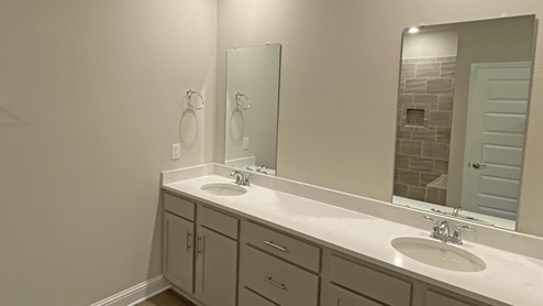 The Delray primary bathroom with dual sink vanity and granite countertops.