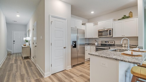 Foyer leading into the kitchen showing peninsula and white shaker cabinetry.