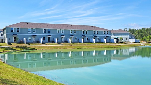 Serene large pond with a walking trail around the perimeter and the townhomes lined in the background.