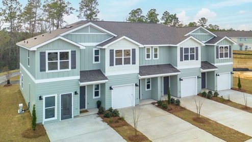 Two-story townhomes with misty green siding with shake accents and one car garage.