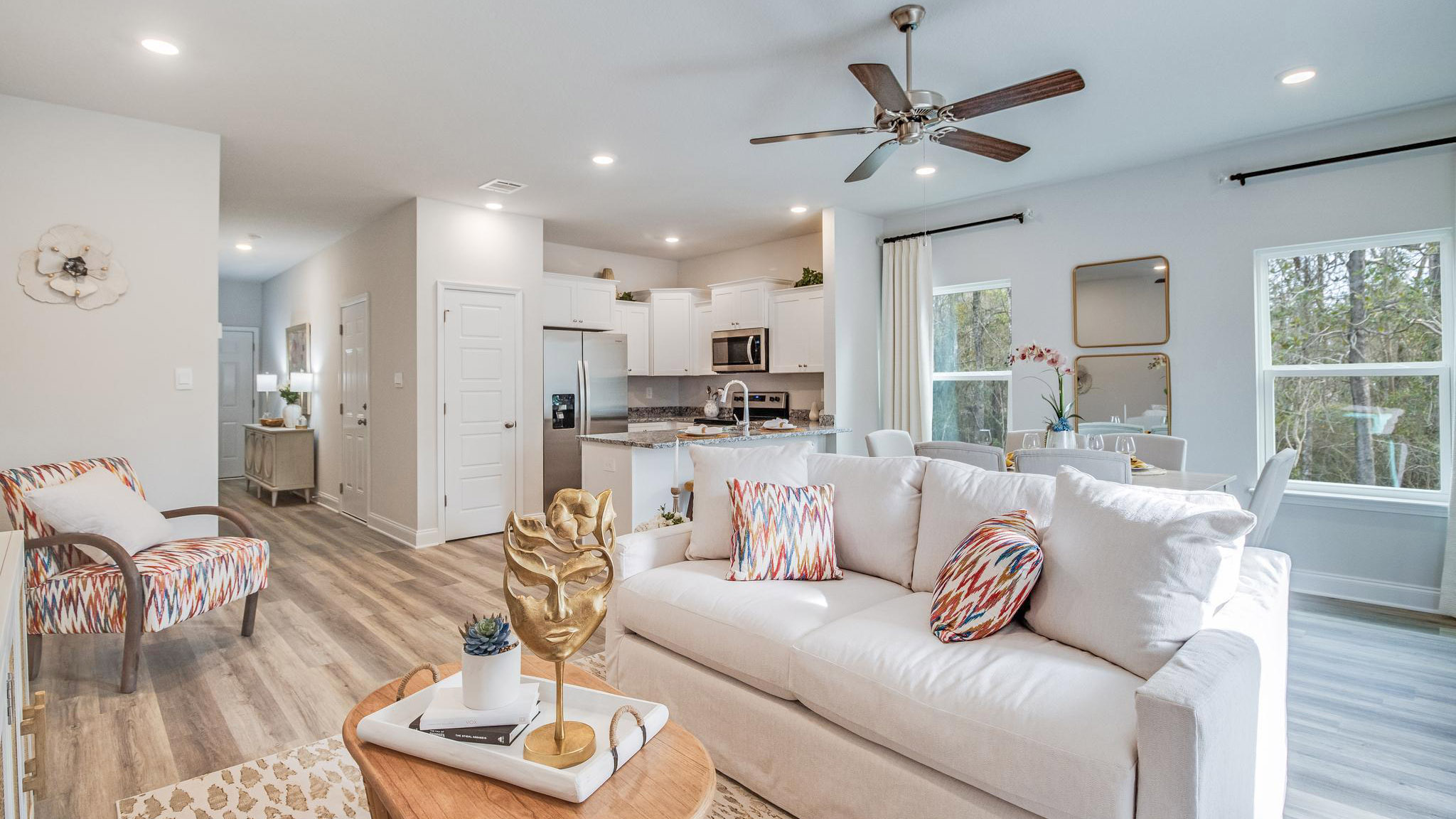 Main living area with clean flooring and natural light connecting to kitchen.