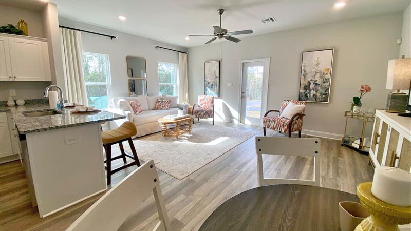 Open concept dining area with simple furnishings connecting to the living area and kitchen.