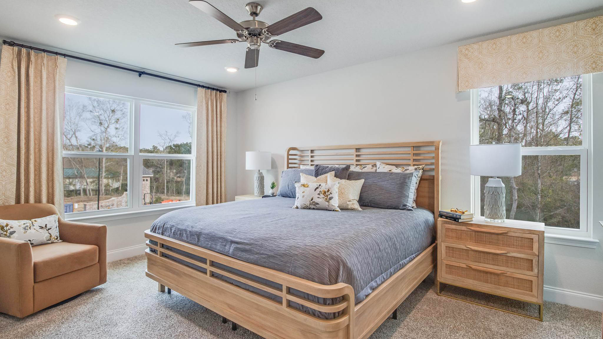 Primary bedroom with carpet, large windows, and simple furnishings.