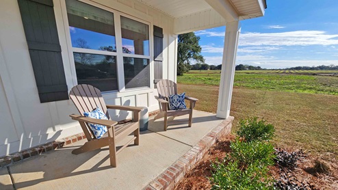 Front porch of model home with two chairs overlooking the landscape.