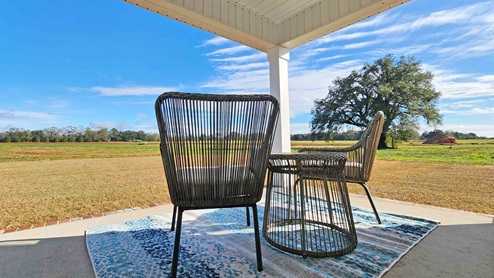 Two chairs on covered back porch looking over landscape.