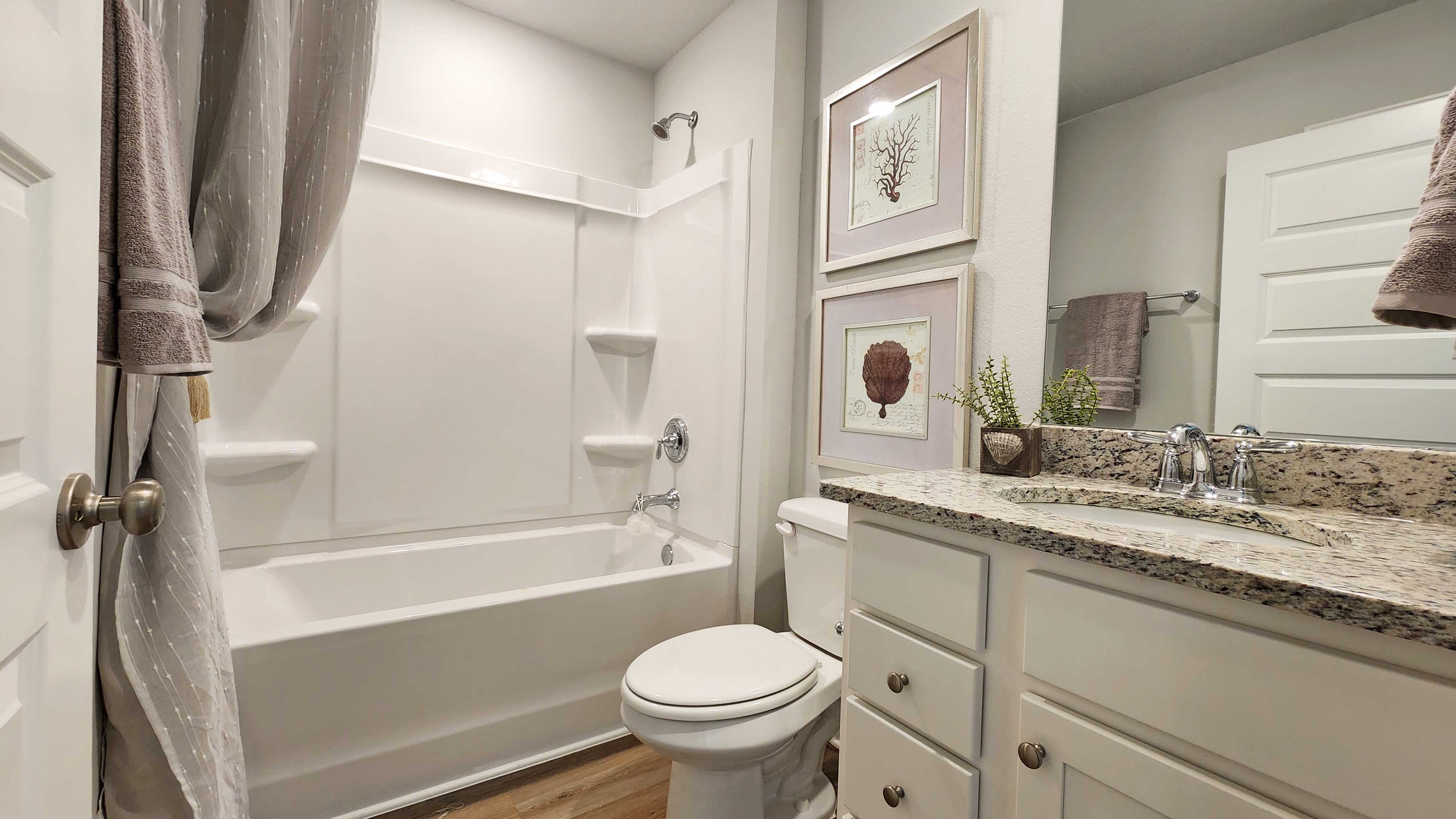 Single vanity with granite countertop and shower/tub combination.