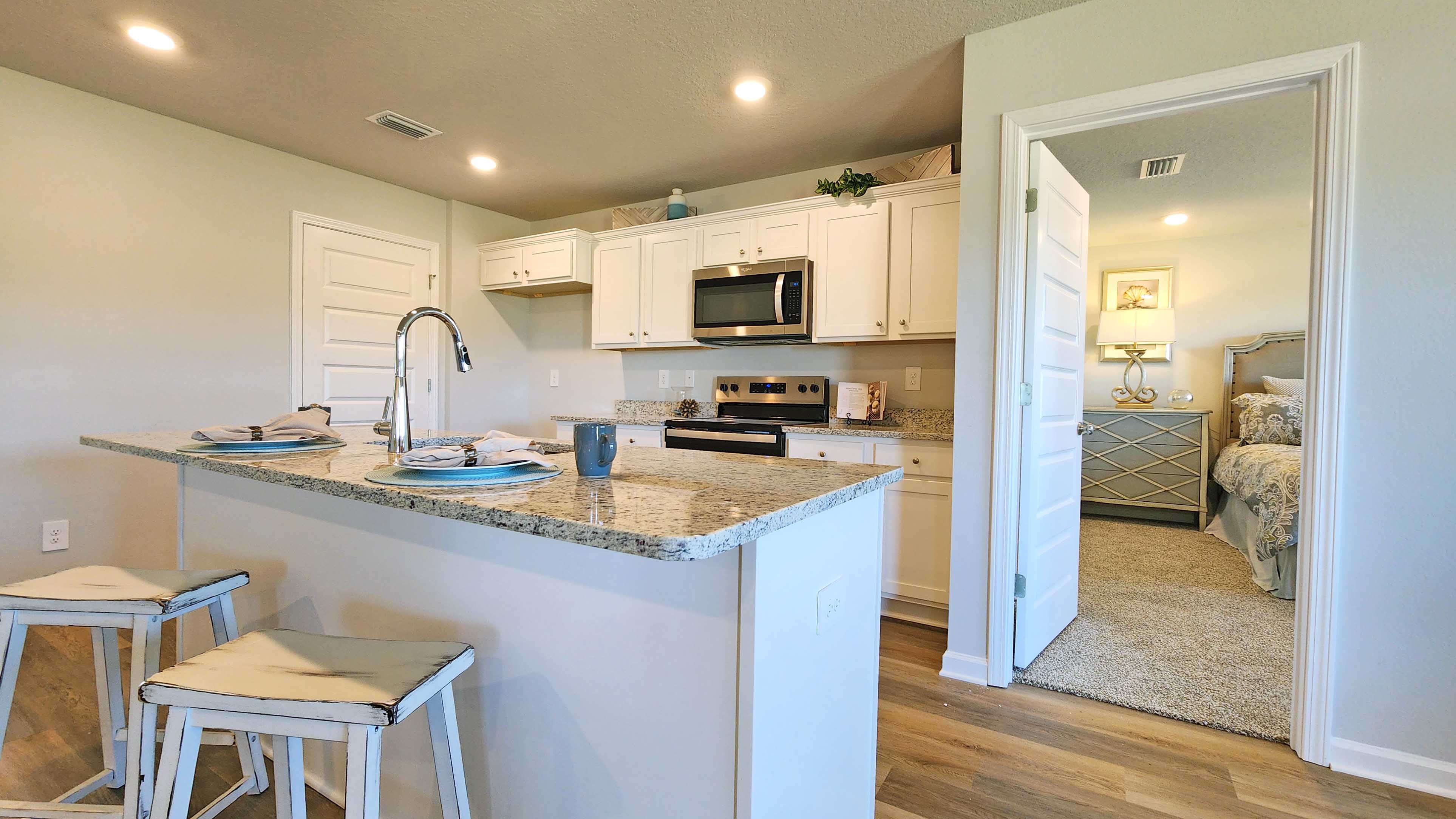 White shaker-style cabinetry with island and granite countertops.