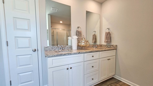 Primary bathroom with dual sink vanity and linen closet.