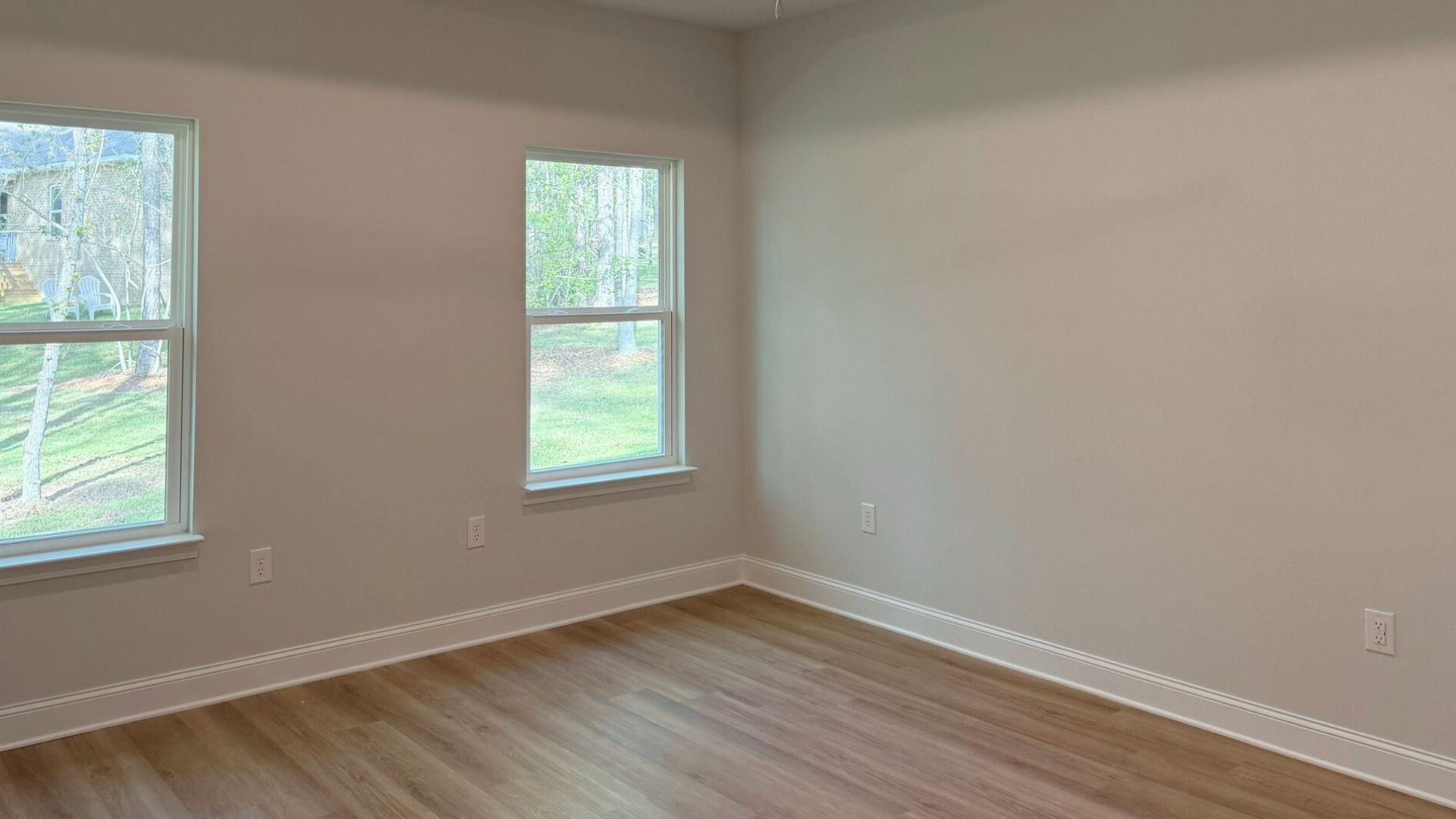 Bedroom with windows and brown flooring.