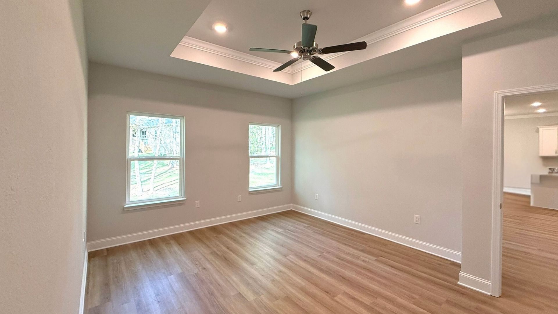 Bedroom with windows and brown flooring.
