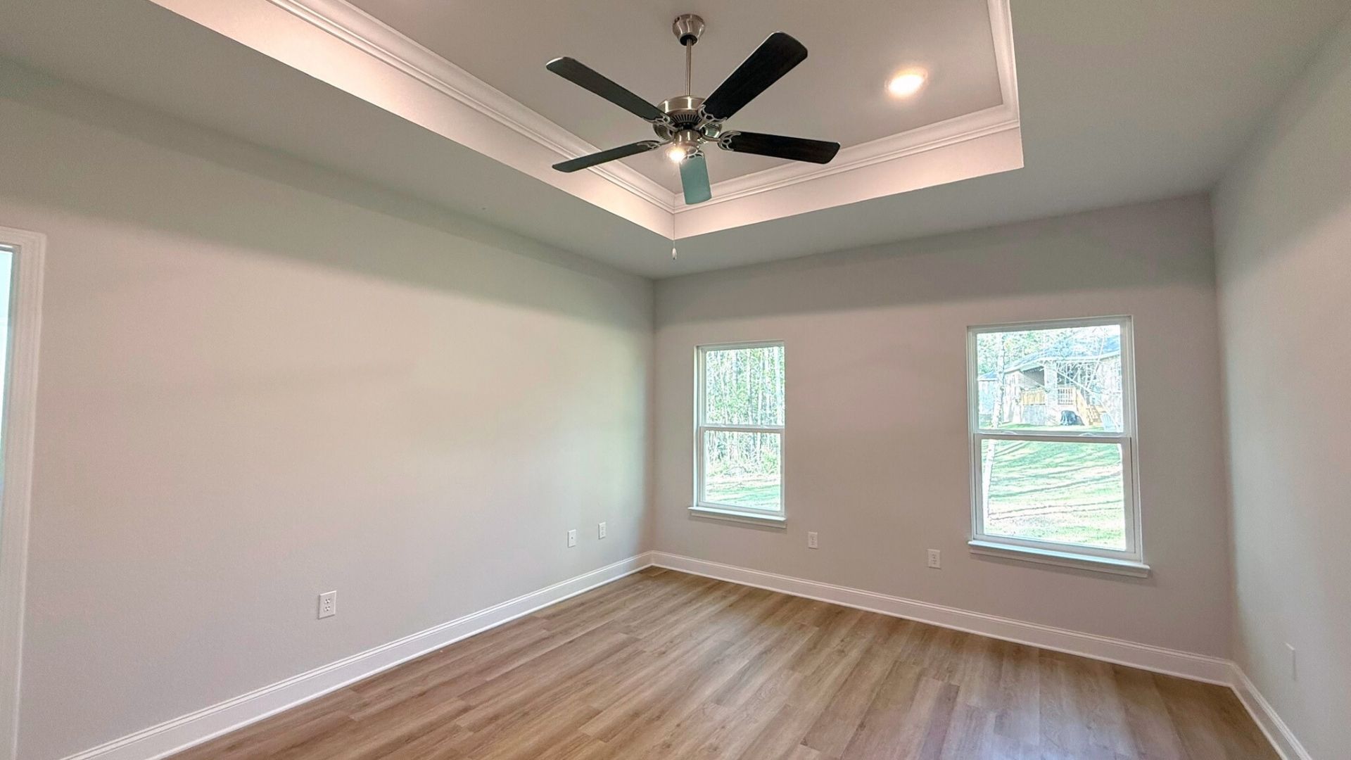 Bedroom with windows and brown flooring.