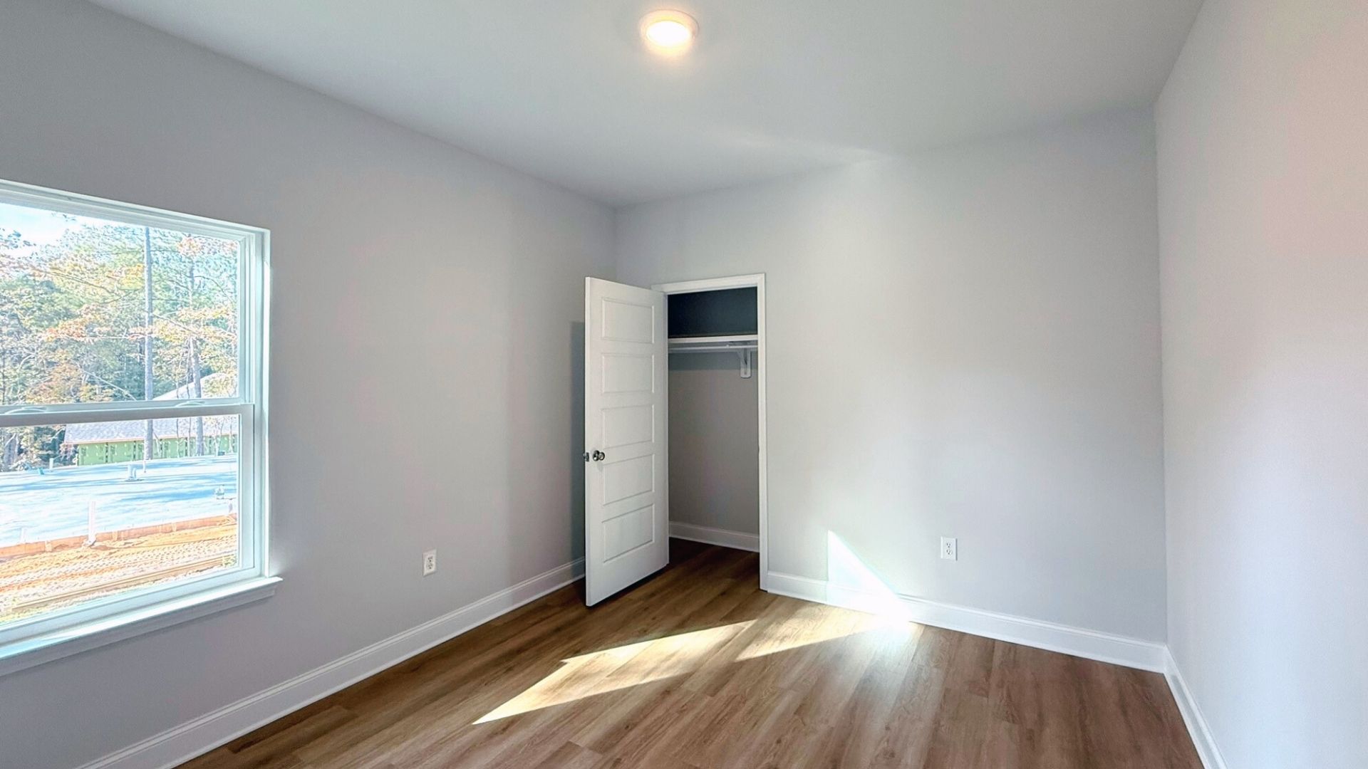 Bedroom with brown flooring and a window.