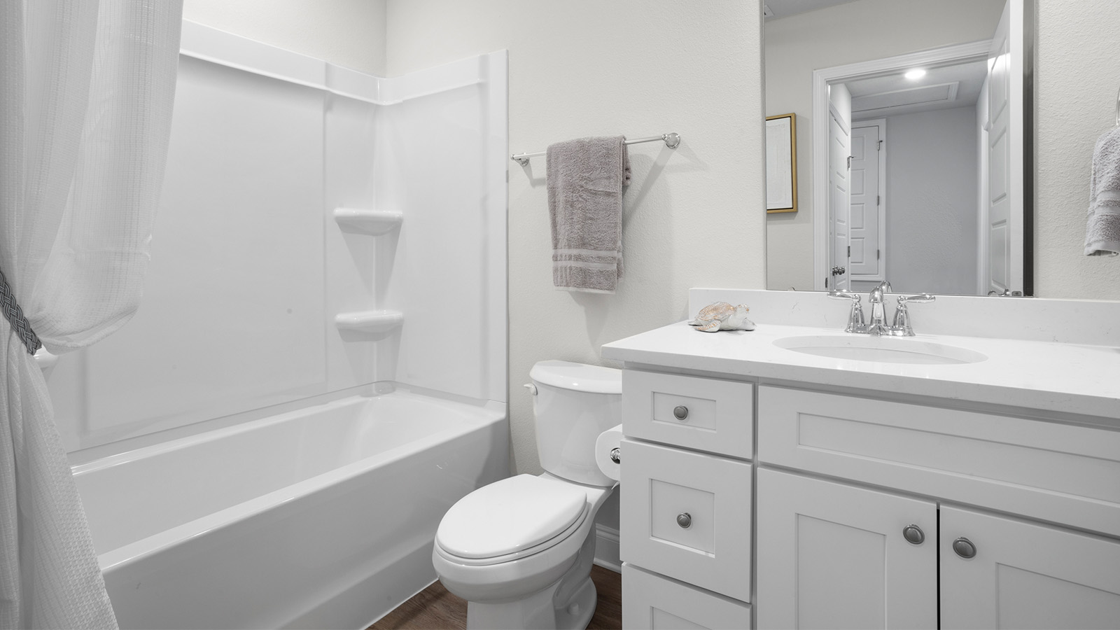 Bright guest bathroom with quartz counters and shower tub combination.