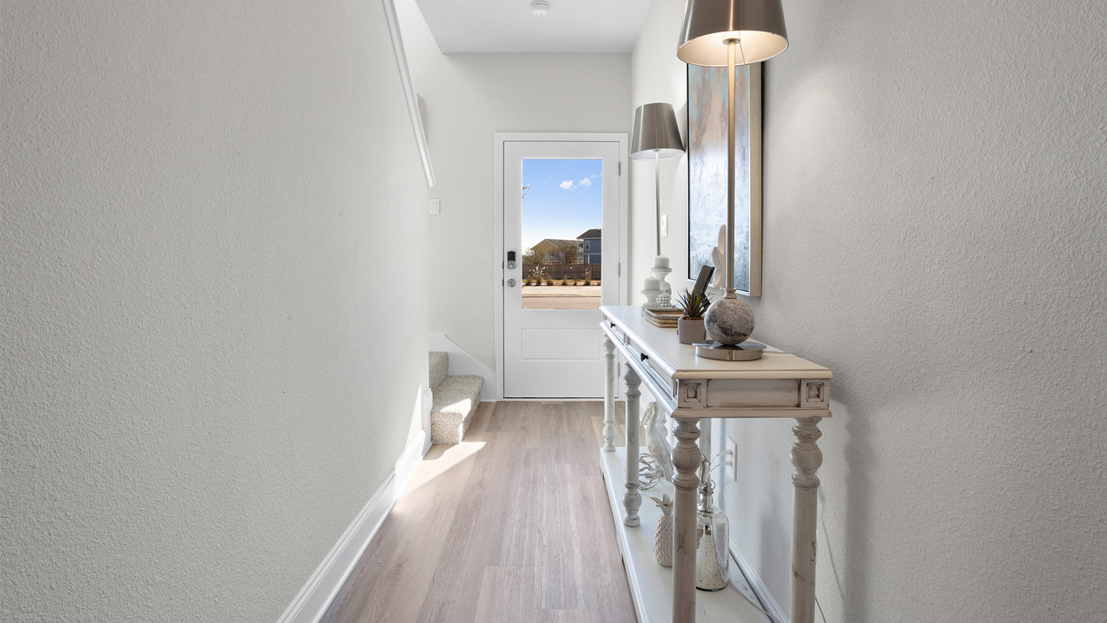 The front hallway is stylishly decorated with artwork and a console table in a new D.R. Horton townhome.