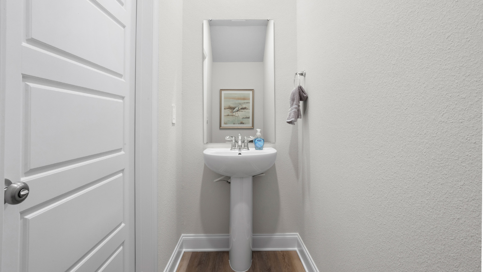 A small powder room with a pedestal sink is tucked away in a new D.R. Horton townhome.