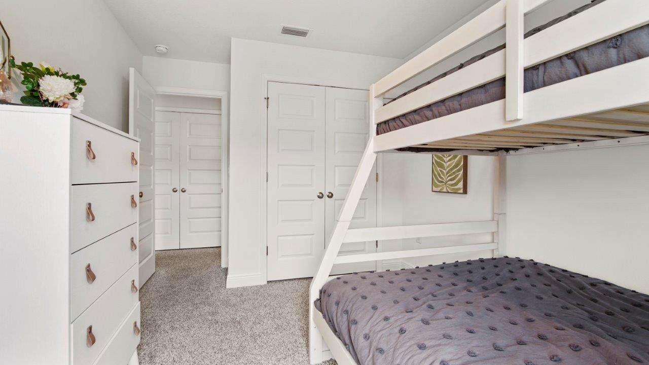 Bright guest room featuring plush carpet and a well sized closet.