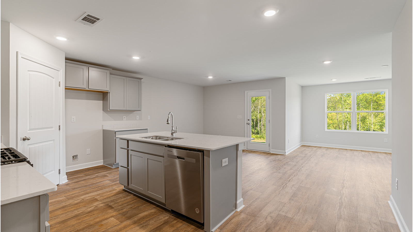 Functional kitchen featuring quartz counters, LVP flooring, and modern appliances.