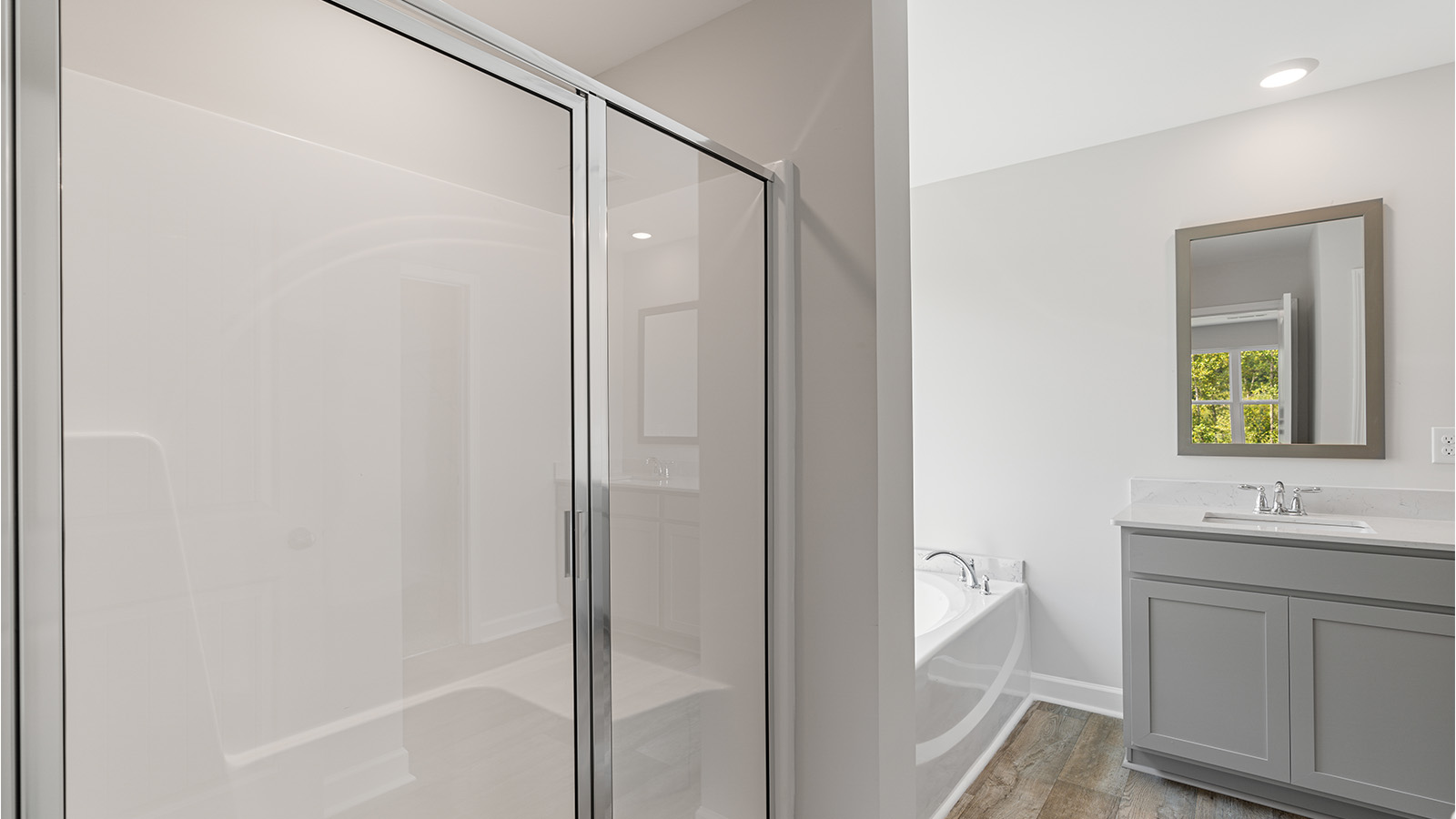 Luxury primary suite featuring a walk in closet, dual vanities, and a separate tub and shower.