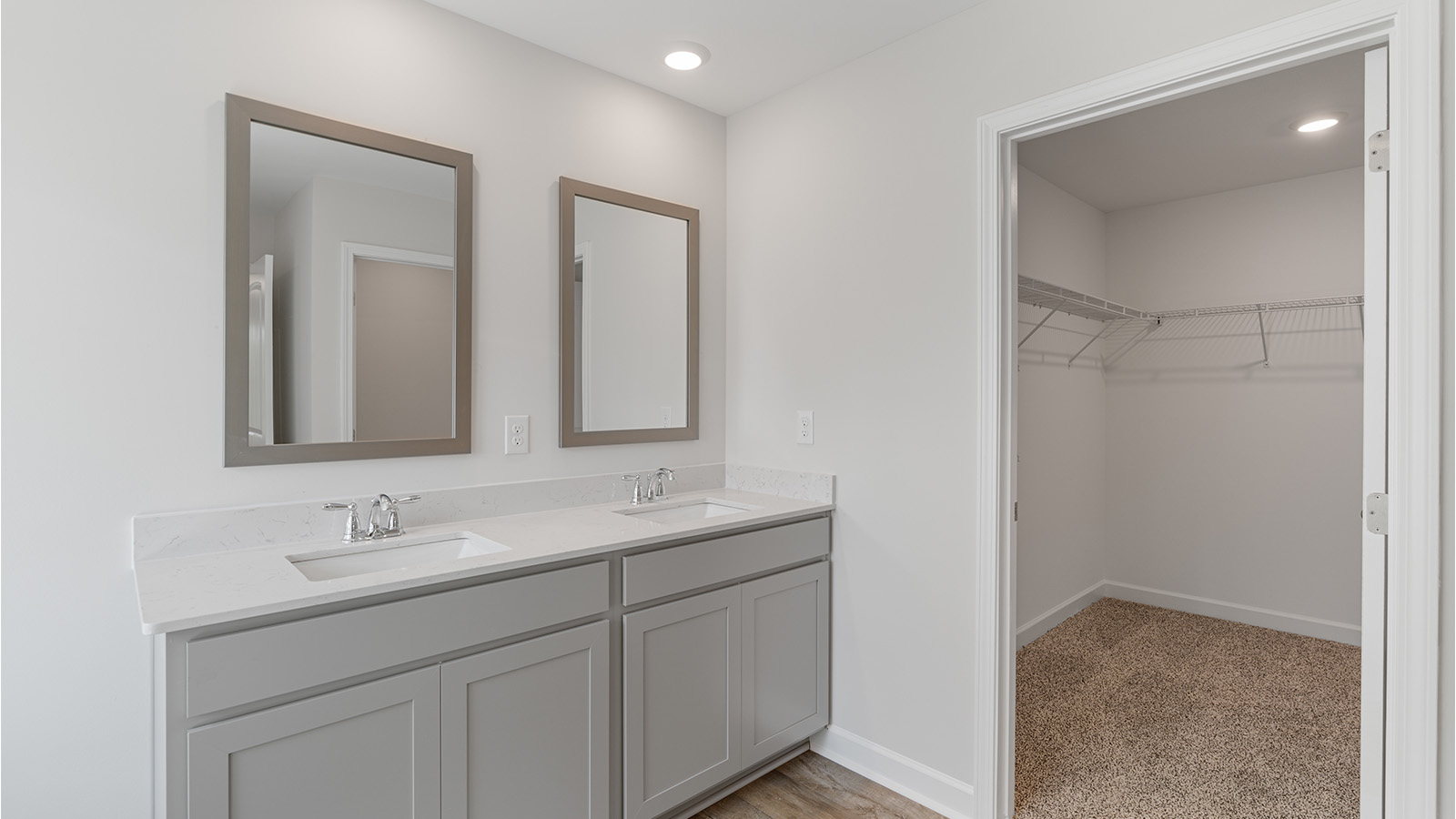 Luxury primary suite featuring a walk in closet, dual vanities, and a separate tub and shower.