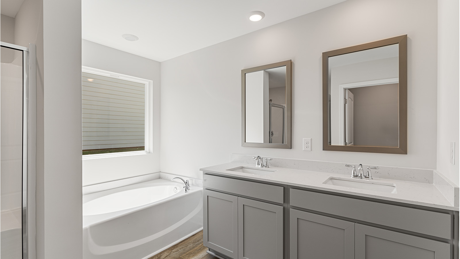 Luxury primary suite featuring a walk in closet, dual vanities, and a separate tub and shower.