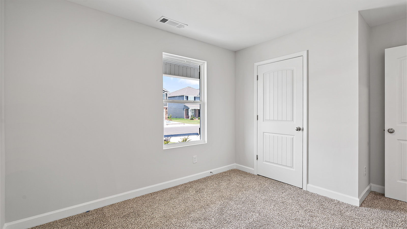 Spacious guest bedroom with soft carpet and full closet