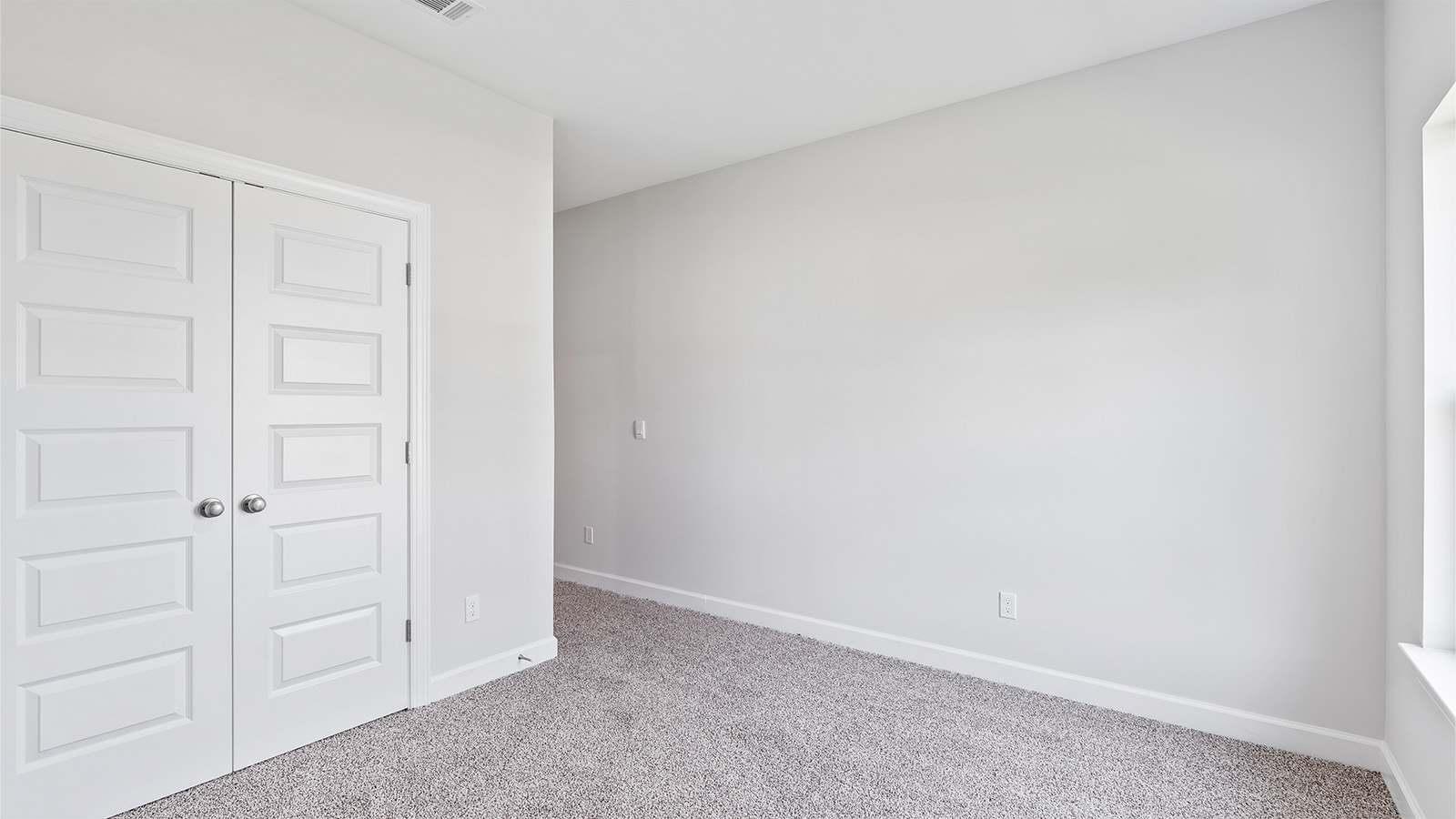 Spacious guest bedroom with soft carpet and full closet