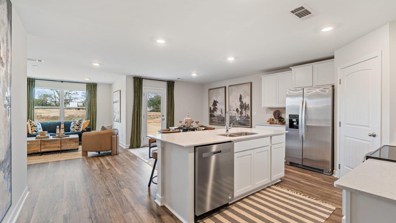 Open concept living room with LVP flooring and seamless flow to the kitchen and dining area.