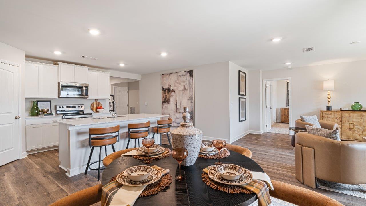 Open concept living room with LVP flooring and seamless flow to the kitchen and dining area.