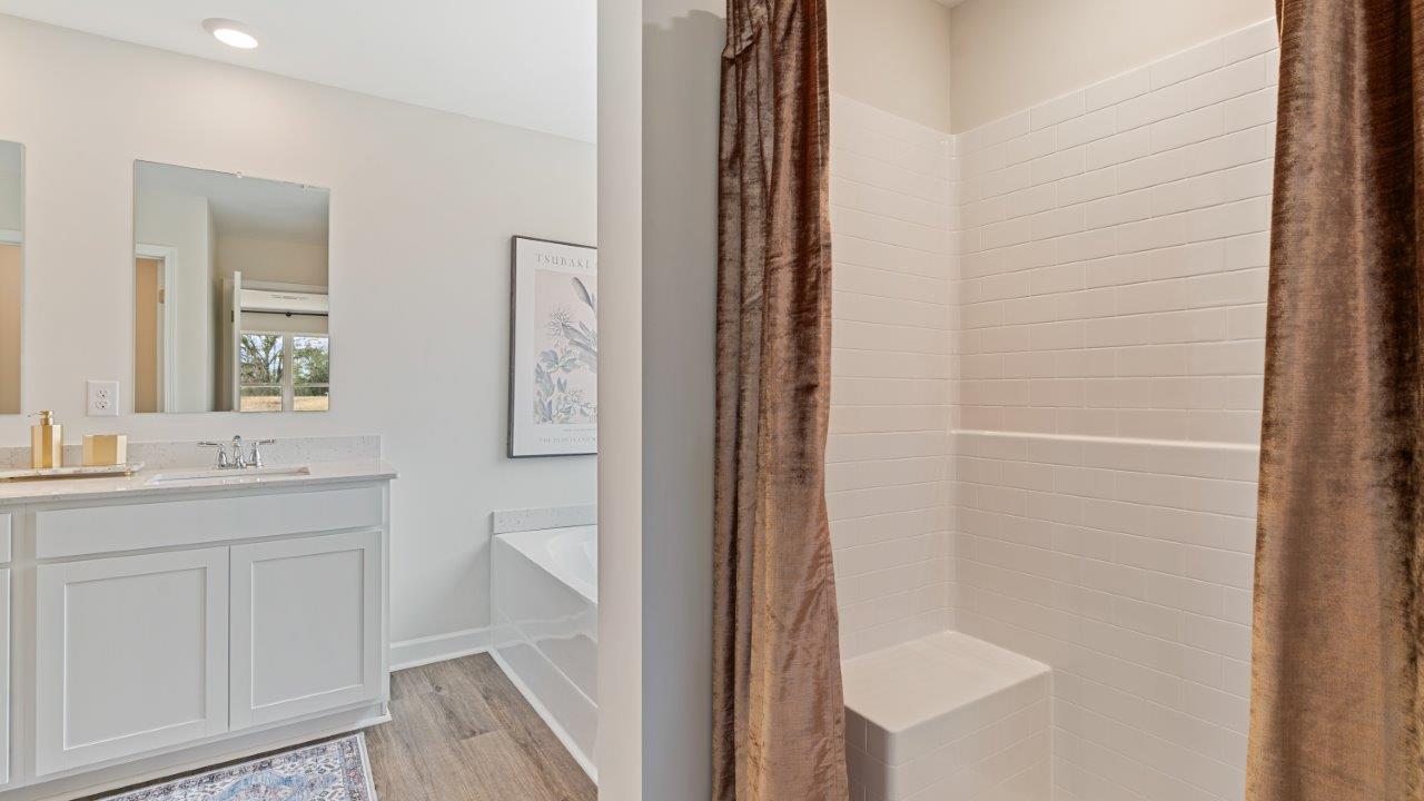 Bright primary bathroom with quartz countertops, a garden tub, and a standalone shower.
