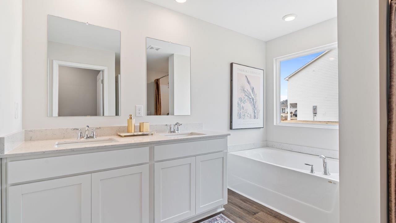 Bright primary bathroom with quartz countertops, a garden tub, and a standalone shower.
