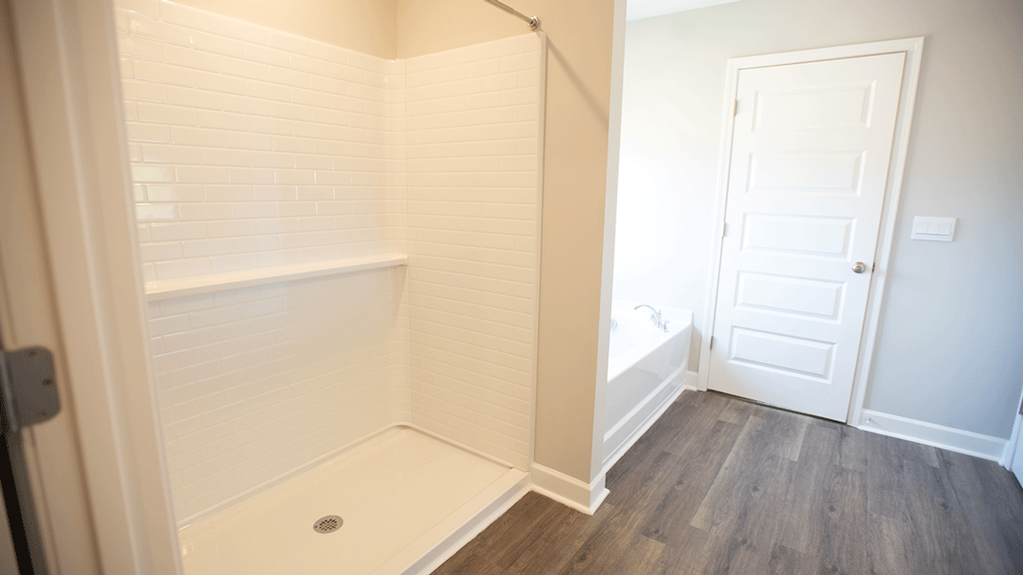 Bright primary bathroom with quartz countertops, a garden tub, and a standalone shower